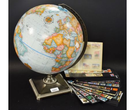 A 1970s globe on stand with a collection of world stamps including Spain, Vietnam, Peru