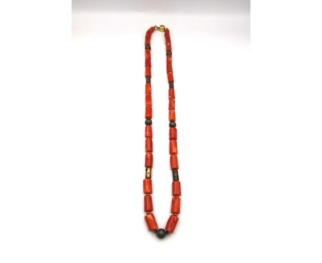 A vintage coral necklace with cylindrical metal pierced beads and gold plated spacers. Fastens with a hook and push cube clas