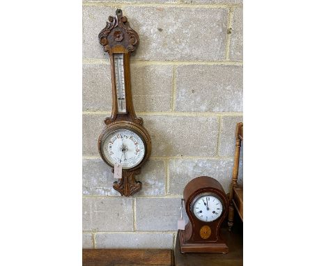 An Edwardian inlaid mahogany tear drop mantel clock, height 34cm and a carved oak aneroid wheel barometer, height 86cm