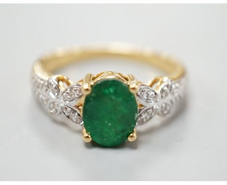 A modern 18ct gold and single stone emerald set dress ring, with diamond chip set shoulders, size R, gross weight 5.5 grams.