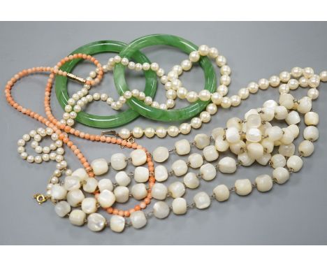 Two single strand cultured pearl necklaces, one with 9ct gold clasp, two green glass bangles, a coral bead necklace and a mot