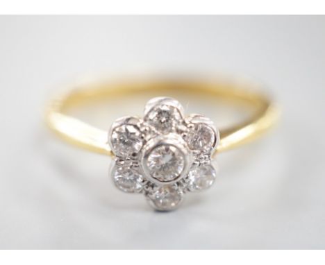 A modern 18ct gold and collet set seven stone diamond set flower head cluster ring, size O, gross weight 3.7 grams, total dia