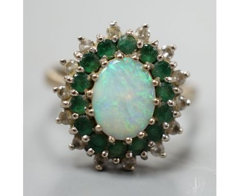 An 18ct white metal, white opal, emerald and diamond set oval cluster ring, size O, gross weight 6.2 grams.