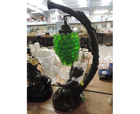A lamp in the form of a cherub riding atop a horn of plenty with illuminated grape bunch