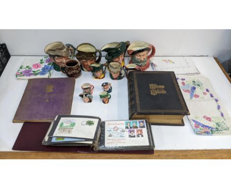 A mixed lot to include Royal Doulton character jugs, vintage lace tablecloths, first day cover stamps, a large copy of the Bi