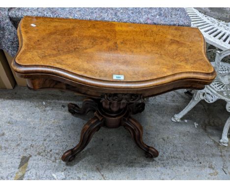 An early Victorian walnut card table, folded over top with serpentine front, inset baize, supported on a plated baluster colu