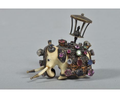 A 19c Indian miniature ceremonial ivory elephant decorated with gilt metal ceremonial costume, jewelled and supporting a lamp