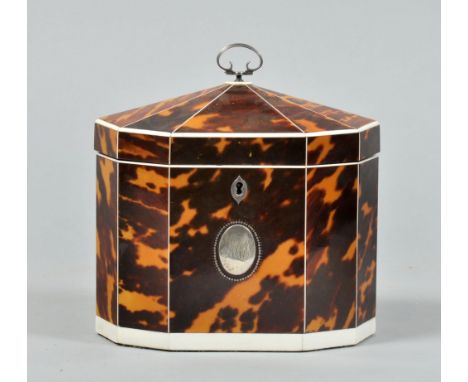 A George III tortoiseshell tea caddy of decagonal form with white bone line inlay and edging and having an oval silver motif,