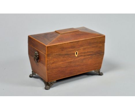 A late Regency rosewood two compartment tea caddy of sarcophagus form with slight facet domed hinged cover, with satinwood li