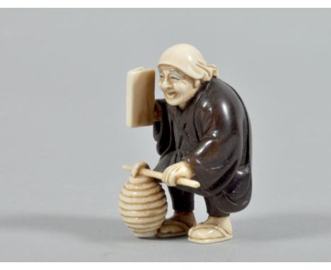 A 19c wood and ivory netsuke carved as a figure with a lantern and a book in the right hand, base with mother of pearl tablet