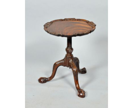 A George III mahogany Chippendale style lamp/kettle stand, the circular top with a carved raised border, on a wrythen carved 
