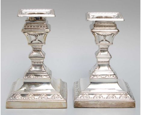 A Pair of Victorian Silver Candlesticks, by Henry Wilkinson and Co., London, 1891, on square base with husk swags, the shaped