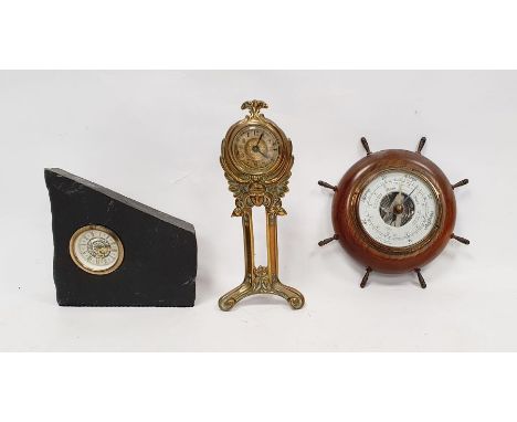 An Art Nouveau brass clock on twin supports with triform base, the mount decorated with female mask and typical foliate swirl