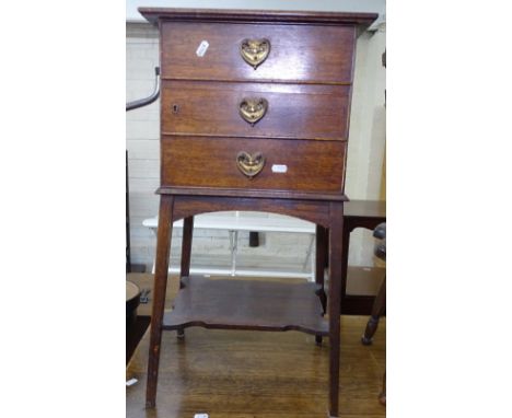 An Arts and Crafts oak smoker's stand, with the dummy drawer front revealing a shelf and drawer fitted interior, on splayed l