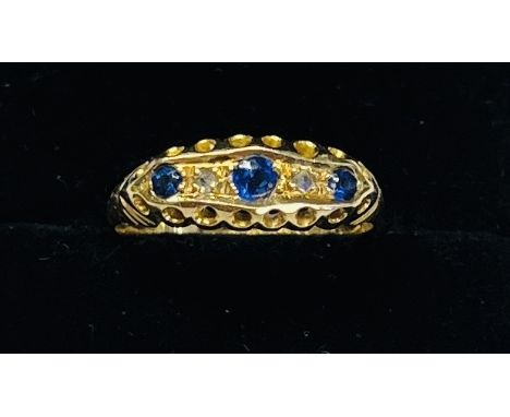 An 18ct yellow gold three stone sapphire and diamond ring, size M/N.