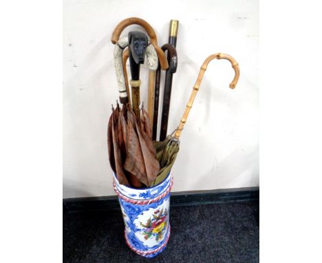 An Italian glazed ceramic stick stand containing vintage walking sticks and parasols 