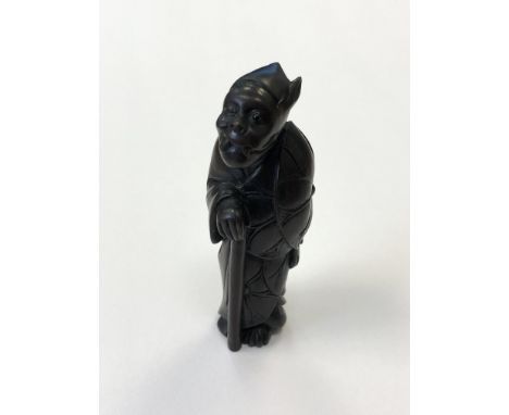 A Japanese carved hardwood netsuke of a figure holding a staff, signed, height 6.5cm