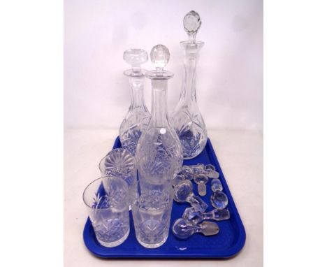 A tray containing three cut glass decanters with stoppers together with a quantity of decanter stoppers and a set of four cut