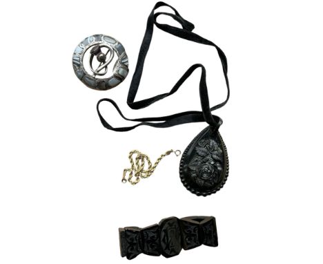 A teardrop shaped Whitby jet pendent with a deep carved central rose motif and bead effect boarder, hanging on a velvet ribbo