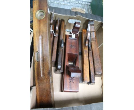 A box containing a selection of vintage wooden planes and a spirit level 