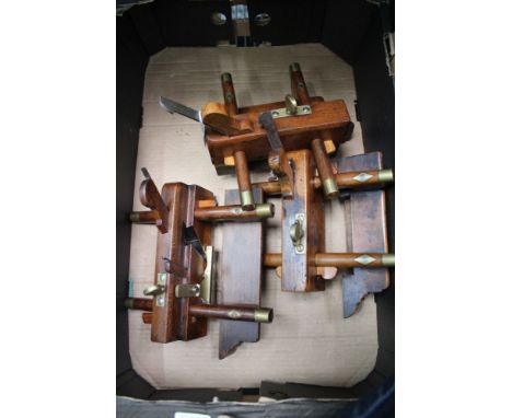 A box containing three vintage wooden adjustable woodworking ploughs 