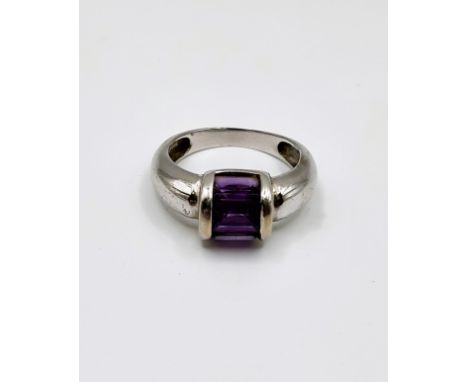 An 18ct white gold ring with three baguette cut purple gemstone, channel set, 4.6g, 