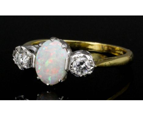 A modern 18ct gold mounted opal and diamond three stone ring, the central oval cut opal approximately .75ct shouldered by two