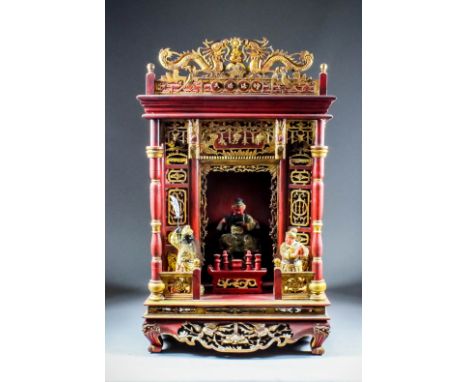 A Chinese carved, red painted and giltwood home altar surmounted by two dragons flanking a god, with moulded cornice pierced 