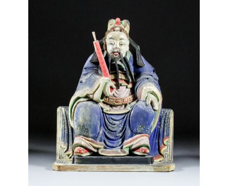 A Chinese carved polychrome wood seated figure of a Ming Dynasty Official - A bearded man holding a scroll in his right hand,