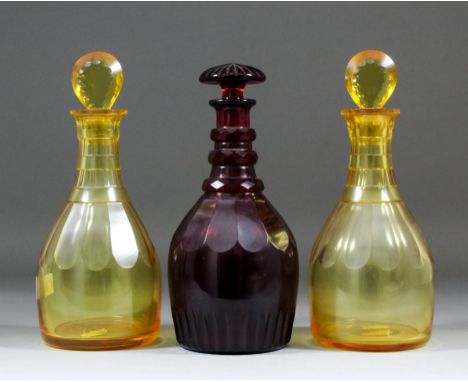 A late Georgian deep ruby glass panel cut decanter and mushroom stopper, 10ins high, and a pair of amber tinted glass panel c