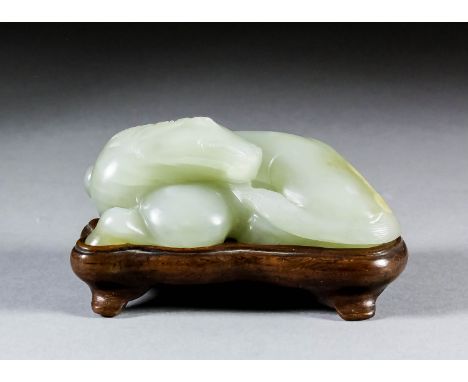 A Chinese pale celadon jade carving of a recumbent horse with brown inclusion to back, 3ins (7.8cm) overall x 1in (2.6cm) hig