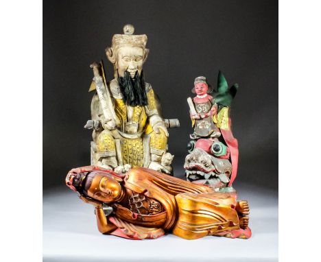 A large Chinese carved polychrome and giltwood seated figure of a bearded deity holding a sword and a flag in his right hand,