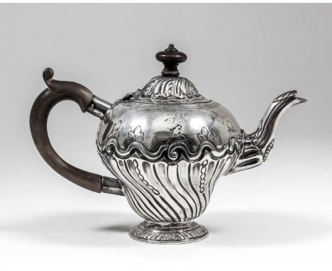 An 18th Century silver teapot of baluster shape, the domed cover and body embossed with spiral reeded, fluted and scroll orna