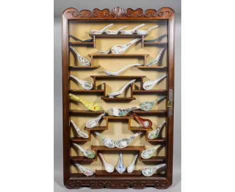 A collection of thirty Chinese porcelain spoons, variously painted, contained in hardwood display case fitted shelves enclose