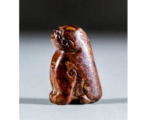 A Chinese brown jade carving of a seated dog, 1.75ins (4.5cm) high (Ming Dynasty - drilled for suspension - rubbed) Note : Wi