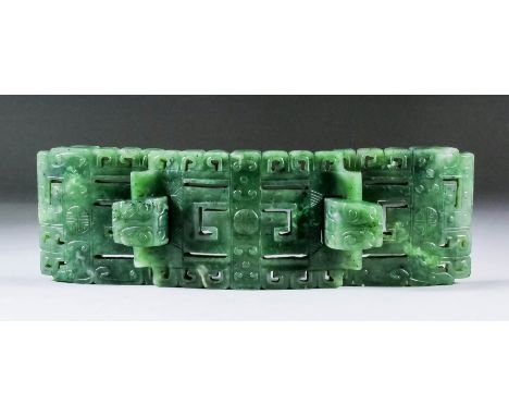 A Chinese spinach green jade belt buckle in three sections, finely carved and pierced with archaic symbols, 7.25ins (18.4cm) 
