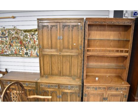 A suit of Old Charm oak furniture including a secretaire cupboard unit, a book shelf with under cupboard and a side board wit