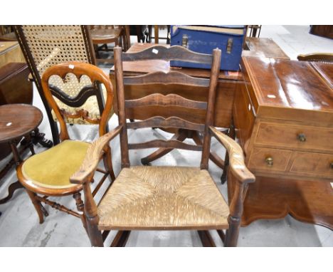 An early 20th century oak framed rocking chair with ladder back and rush seat