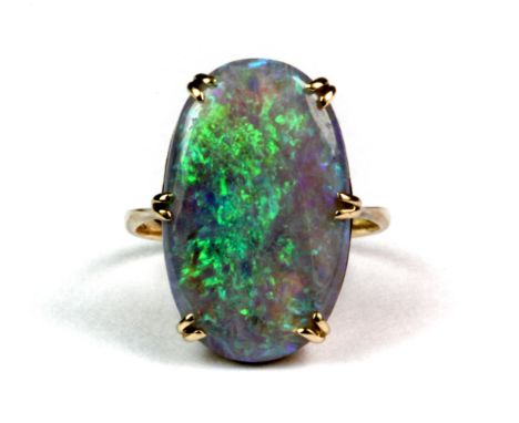 A yellow metal (tested 18ct gold) ring set with a large oval cabochon cut opal, L. 2cm, (J.5).