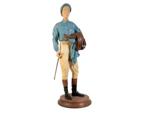 A 1960'S PLASTER CAST MODEL OF A JOCKEY (Lester Piggot) dressed in racing colours blue silks and holding a saddle and a jocke