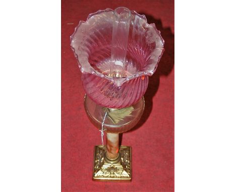 An early 20th century oil lamp having a pink tinted swirled glass shade above a clear glass reservoir on an onyx column and p
