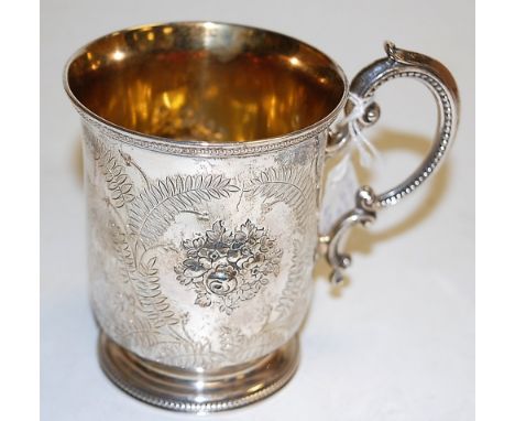 A mid-Victorian silver christening mug, having gilt-washed bowl, leaf engraved ground with opposing leaf and flower chased re