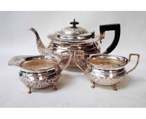 An Asian silver three piece Tea Service of typical oval form, embossed floral and scroll decoration, on four paw feet, tea po