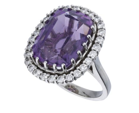 An amethyst and diamond cluster ring, the cushion-shaped amethyst within a surround of brilliant-cut diamonds, mounted in 18c