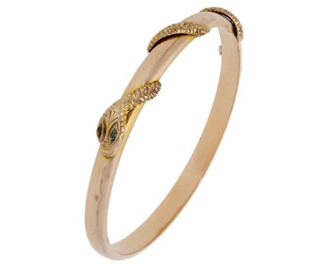 A 9ct gold serpent bangle, 1923, with applied partial coiled serpent decoration, the head with green gem-set eyes, maker’s ma