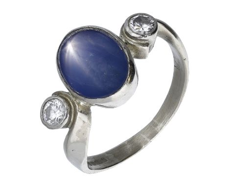 A star sapphire and diamond ring, the oval star sapphire cabochon with a brilliant-cut diamond to either side, between scroll
