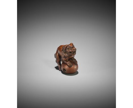 A WOOD NETSUKE OF A SHISHI ON A LARGE BALL Unsigned Japan, late 18th to early 19th century, Edo period (1615-1868)The shishi 