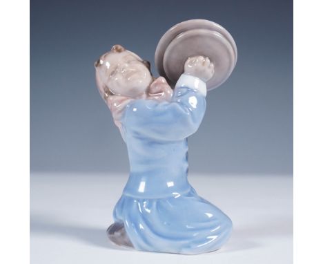 Crafted by the renowned Royal Copenhagen of Denmark, this porcelain figurine features a young girl joyfully clashing cymbals.