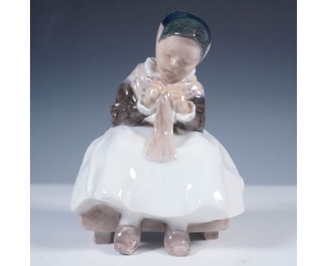 Charming Royal Copenhagen porcelain figurine titled Amager Girl Knitting, model number 1314. Designed in soft muted tones, th