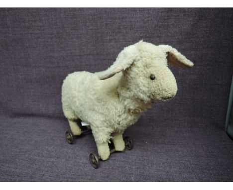 A possible Steiff or Steiff style straw filled white plush Lamb on wheels having stitched nose and replacement eyes, no butto